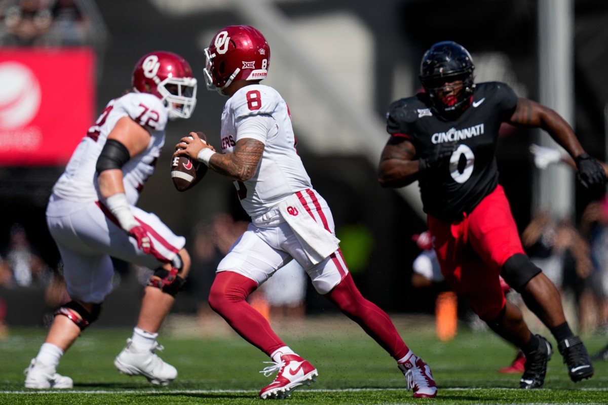 Oklahoma Sooners quarterback Dillon Gabriel (8) scrambles away from Cincinnati Bearcats defensive end Jowon Briggs (0) in the fourth quarter of the NCAA Big 12 football game between the Cincinnati Bearcats and the Oklahoma Sooners at Nippert Stadium in Cincinnati on Saturday, Sept. 23, 2023. 